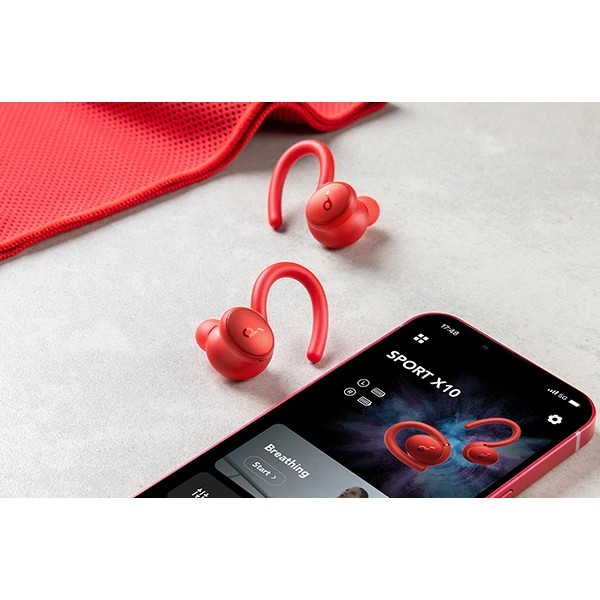 هدفون Soundcore Sport X10 کنار گوشی موبایل، نمایش اندازه جمعوجور و اتصال بلوتوثی برای استفاده روزمره