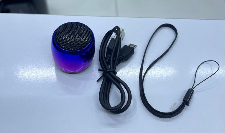 اسپیکر کوچک بلوتوثی Mini رنگ آبی؛ بدنه استوانهای کوچک، کلید تکلمسی روی بدنه و پورت شارژ میکرویواسبی و بند برای حمل محصول
